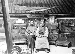 A white man in military uniform sits on the left, while Buyan-Badyrgy, on the right, sits expressionless while wearing traditional Tuvan dress