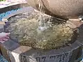 Bowl with coins left by visitors. Fountain "Apple" on top of the Kok-Tobe.