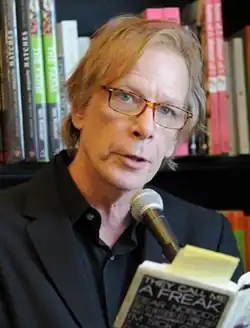 Legs McNeil holds a book with Gillian McCain standing next to him
