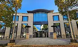 The entrance to a modern, three-floor office building. It features a symmetrical facade with beige stone walls and large windows. In the middle of the central glass front is a sign reading "Rockstar North".
