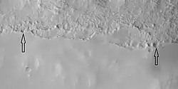 Close view of mantle, as seen by HiRISE under HiWish program Arrows show craters along edge which highlight the thickness of mantle. Location is Ismenius Lacus quadrangle.