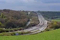long-distance view with woods and fields and a four-lane road curving through it