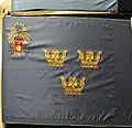 The 1935 colour. The provincial badge of Uppland was added in 1959 in the upper inner corner, where initially the lesser coat of arms of Sweden was.