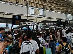 A large crowd of passengers with luggage gathered on the platform at Gare de Lyon in Paris, preparing to board a Ouigo train under the station’s large clock.