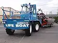 Southport inshore rescue boat on trailer showing special tractor which steers with an articulated front end, which is somewhat wedge-shaped to push obstructions aside