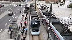View of two Tango tram vehicles arriving at a station taken from a bridge or overpass