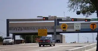 Gantry building labeled "ADDISON AIRPORT TOLL TUNNEL" with lanes for full-service, exact change, and electronic tolling