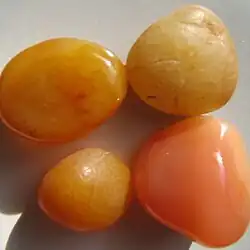 Peach reds and yellows with threadlike mossy and cell-like formations in semi-smooth tumbled agate pebbles.