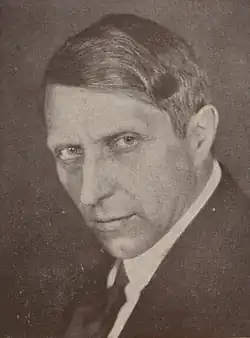 Black and white photograph of a middle-aged man with dark hair in a suit and tie