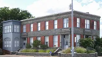 The Badu Building, a red brick and limestone two-story building that is rectangular with a small ell on one end.