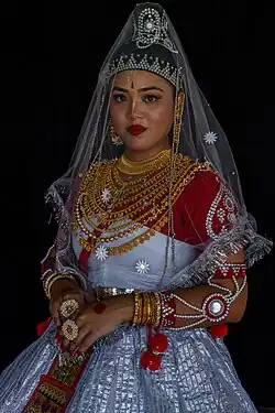 Adding jewelry can obscure or complicate the shape of a neckline. For example, this Meitei woman wears many necklaces as part of her traditional Bangladeshi Meitei clothing. These necklaces create the perception of a rounded neckline, despite the V-shaped neckline of the clothing underneath.
