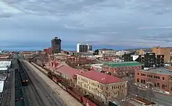 A downtown district with historic brick buildings fronted a railroad track, and various high-rise buildings standing in the background.