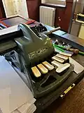 six key braillewriter with beige keys and a dark green, metal machine.