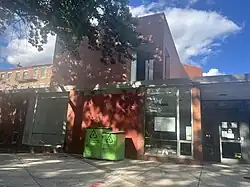 An image of the entrance to the Boston Public Library South End branch. The building is a two story brick building with a glass door.