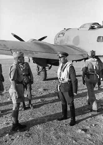four men in military uniforms standing in front of a propeller-driven aircraft