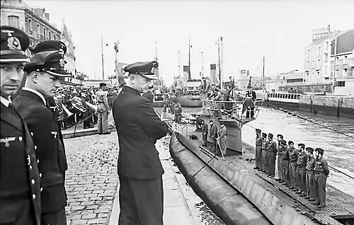 Several people looking at a submarine with its crew on the deck