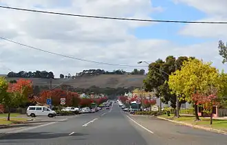 Henty Street (Glenelg Highway), the main street of Casterton. Note the Fleur-de-Lis and the name of the town carved into the hill in the background.