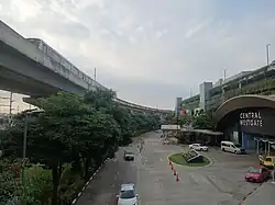 Central WestGate shopping mall, seen from the footbridge connecting its main building to its Auto1 tire shop, a Purple Line train is visible in the background.