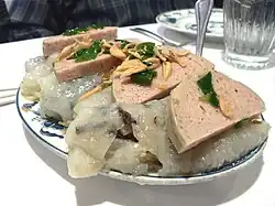 Sliced chả lụa served over bánh cuốn, garnished with fried shallots
