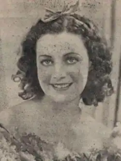A smiling young white woman with dark curly hair