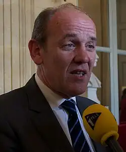 A relatively old man in a suit giving an interview