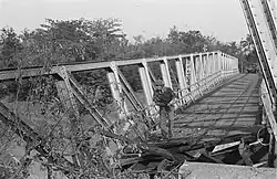 A Dutch soldier examines a destroyed bridge in Java, 1947