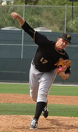 Dovydas Neverauskas with his arm outstretched in the middle of his pitching motion, in a black Pittsburgh Pirates uniform in 2016 spring training
