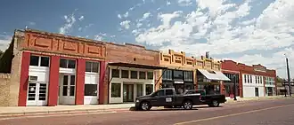 A group of buildings with vehicles parked in front line a downtown street