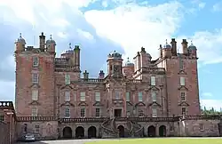 View of the front of Drumlanrig Castle, looking slightly up, standing near the fencing separating the castle itself from the public