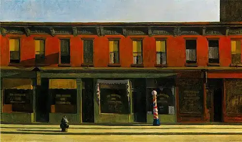 An empty city street lined with storefronts in the early morning light
