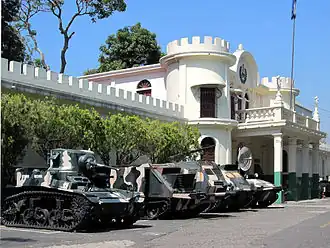 A photograph of El Zapote barracks with military vehicles in front of it