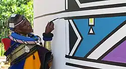 South African artist Esther Mahlangu painting in the distinctive Ndebele house painting style.