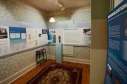 Museum exhibit with interpretive panels, historic photographs, documents, and a mining lamp about the 1927 Columbine Mine massacre at the Lafayette History Museum in Colorado.
