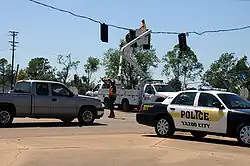 Workers attempting to restore power lines behind a police car