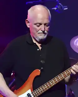 Fedor Frešo wearing a dark polo shirt, playing bass on a darkened stage, looking down at his instrument