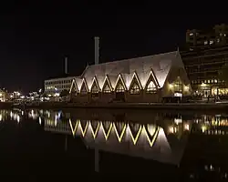 Photograph the fish market at night with a reflection in the water next to it