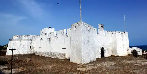 Exterior photograph of Fort Metal Cross, Dixcove, Western Region, Ghana. It is composed of two images stitched together taken from just outside
