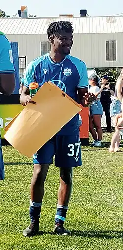 Lifumpa Mwandwe in uniform holding a folder paper sign