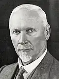 Close-up black-and-white portrait of Jan Smuts wearing a suit against a neutral background with a neutral expression.