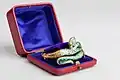 gold and enamel bangle in the shape of a snake, sat in a blue lined box