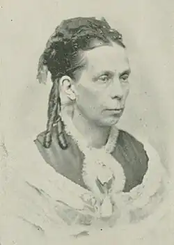 B&W portrait photo of a middle-aged woman with her hair in an up-do with ringlets.