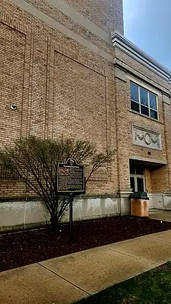 Photo of a brick building with a historic marker in front of it.