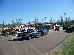 A leveled baptist church with a trucks and cars parked in the driveway