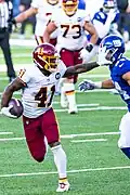 J. D. McKissic applies a fend to the face mask of an opponent during an American football game