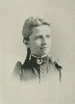 19th-century B&W portrait photo of a woman with her hair in an up-do, wearing a dark, fitted blouse.