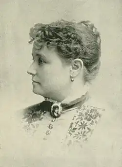19th-century B&W portrait photo of a woman with her hair in an up-do, wearing a dark, fitted blouse.