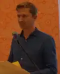 A white man with short blond hair at a public reading.
