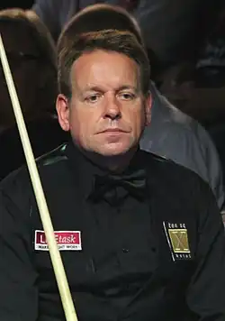 Joe Swail sitting and holding his cue