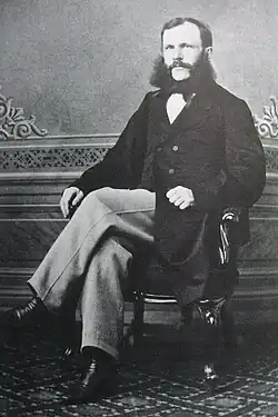 Bomansson with moustache and sideburns sitting cross legged