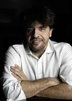 close-up of Karl Deisseroth wearing a white shirt, leaning on folded arms, looking directly at camera with a grin